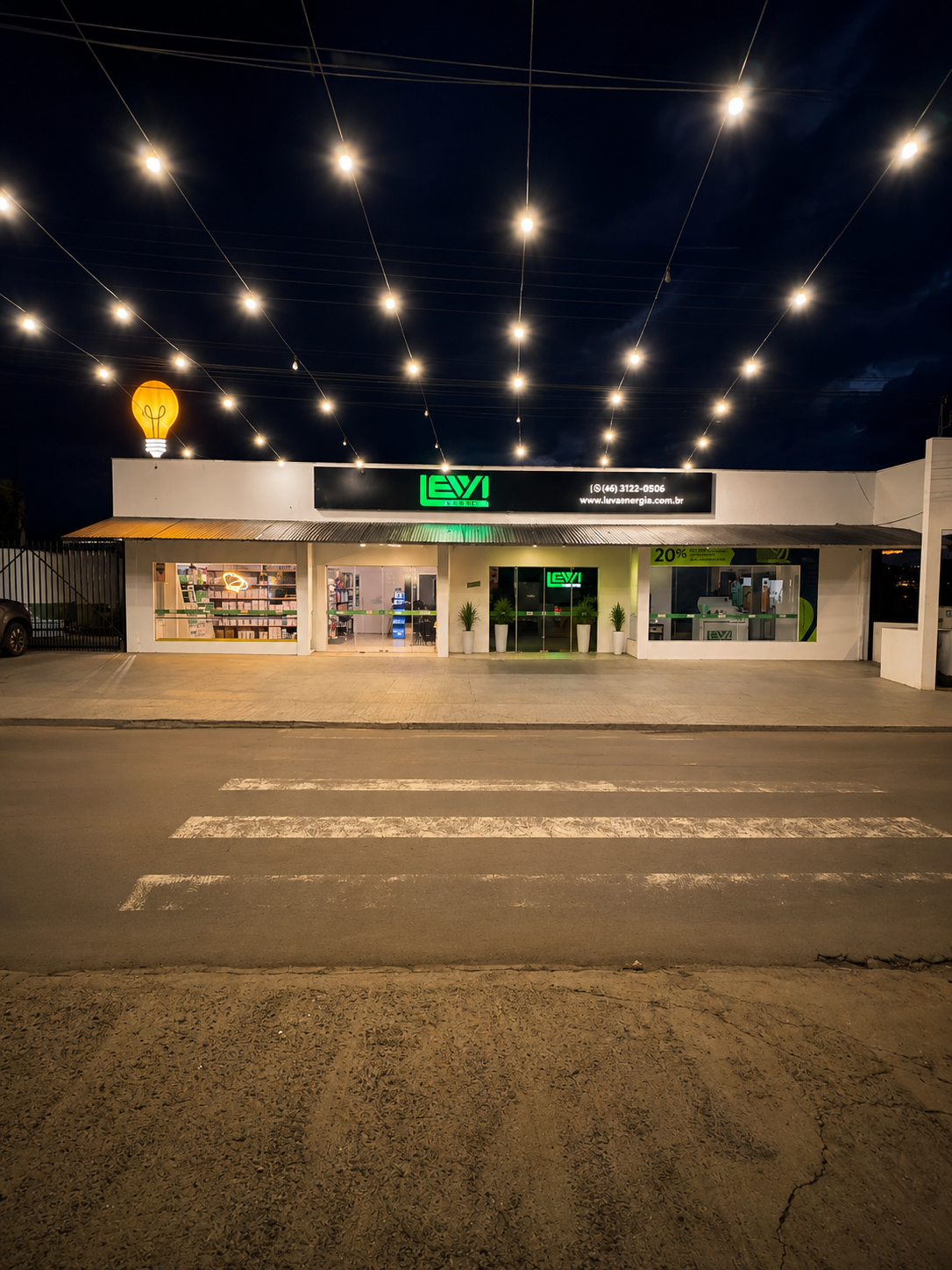 Fachada da loja física LEVA Energia à noite, com letreiro verde iluminado e luzes decorativas